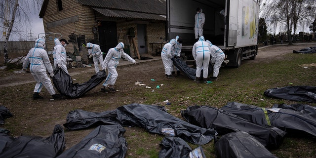 Volunteers load bodies of civilians killed in Bucha onto a truck to be taken to a morgue for investigation, on the outskirts of Kyiv, Ukraine, Tuesday, April 12, 2022.