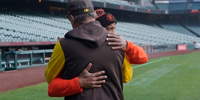 San Diego Padres third base coach Mike Shildt, back to camera, hugs San Francisco Giants first base coach Antoan Richardson after they spoke at a news conference before a game in San Francisco, Wednesday, April 13, 2022.