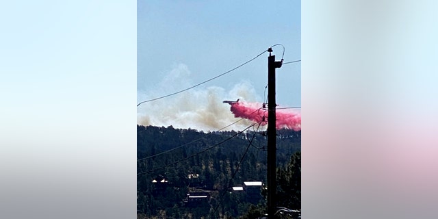 This photo provided by the Village of Ruidoso shows a fire fighting air tanker dropping fire retardant across the mountains near the Village of Ruidoso, N.M., on Wednesday, April 13, 2022. 