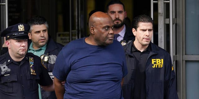 New York City Police, left, and law enforcement officials lead subway shooting suspect Frank R. James, 62, center, away from a police station, in New York, Wednesday, April 13, 2022. The man accused of shooting multiple people on a Brooklyn subway train was arrested Wednesday and charged with a federal terrorism offense.