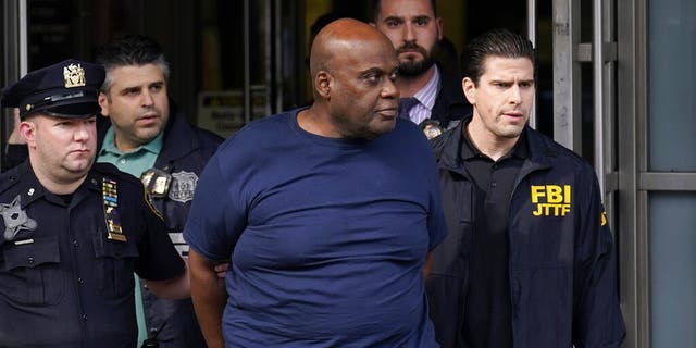 Law enforcement officials lead subway shooting suspect Frank R. James, 62, center, away from a police station, in New York on April 13. The man accused of shooting multiple people on a Brooklyn subway train faces multiple terrorism charges.