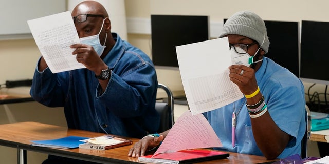 Incarcerated students look at the photograph "The Falling Man," that was part of a discussion during a Mount Tamalpais College English class called Cosmopolitan Fictions at San Quentin State Prison April 12, 2022, in San Quentin, Calif. The community college, the first in California with a campus inside a prison, is the latest addition to San Quentin's numerous rehabilitation programs that have made it a desired destination for inmates throughout the state.