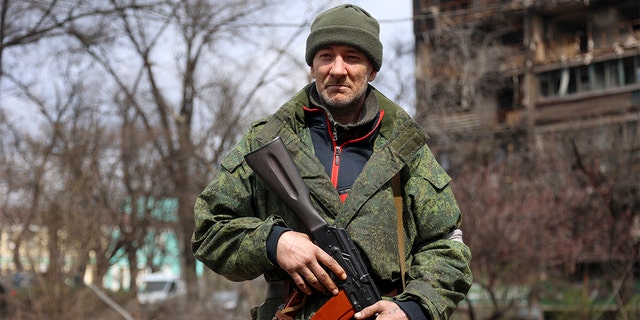 An armed serviceman of Donetsk People's Republic militia patrols a street in an area controlled by Russian-backed separatist forces in Mariupol, Ukraine, Friday, April 15, 2022. Mariupol, a strategic port on the Sea of Azov, has been besieged by Russian troops and forces from self-proclaimed separatist areas in eastern Ukraine for more than six weeks. 