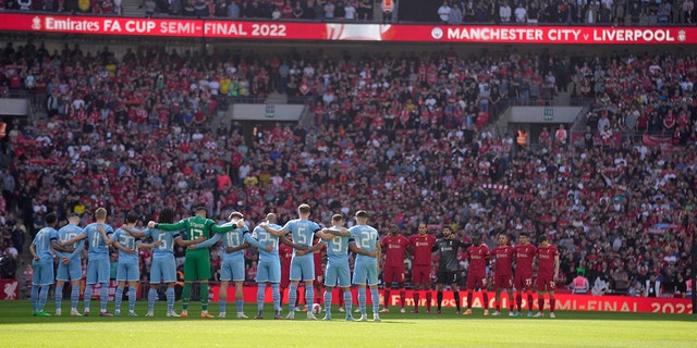 Manchester City, left, and Liverpool players stand for a moment of silence to remember those who died in the 1989 Hillsborough disaster, before the English FA Cup semifinal soccer match between Manchester City and Liverpool at Wembley stadium in London, Saturday, April 16, 2022. 