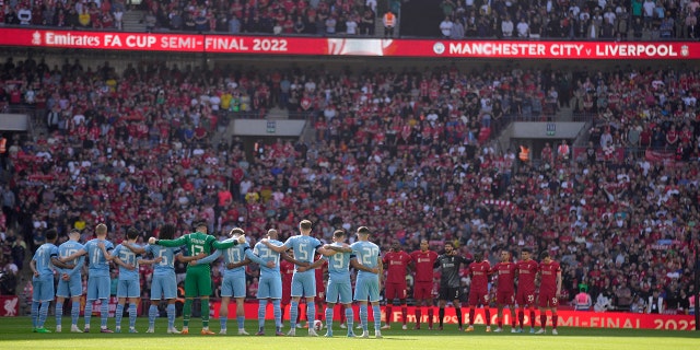 Manchester City, left, and Liverpool players stand for a moment of silence to remember those who died in the 1989 Hillsborough disaster, before the English FA Cup semifinal soccer match between Manchester City and Liverpool at Wembley stadium in London, Saturday, April 16, 2022.
