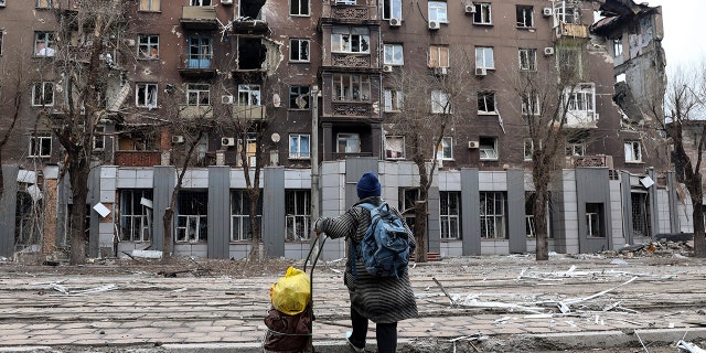 A local resident looks at a damaged during a heavy fighting apartment building near the Illich Iron & Steel Works Metallurgical Plant, in an area controlled by Russian-backed separatist forces in Mariupol, Ukraine, Saturday, April 16, 2022.