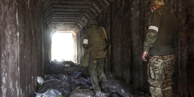 Servicemen of the Donetsk People's Republic militia look at bodies of Ukrainian soldiers placed in plastic bags in a tunnel, part of the Illich Iron & Steel Works Metallurgical Plant, the second largest metallurgical enterprise in Ukraine, in an area controlled by Russian-backed separatist forces in Mariupol, Ukraine, Monday, April 18, 2022. Mariupol, a strategic port on the Sea of Azov, has been besieged by Russian troops and forces from self-proclaimed separatist areas in eastern Ukraine for more than six weeks.