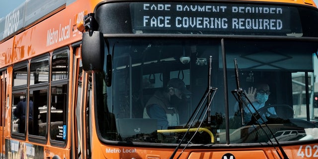 A Los Angeles Metro bus with an electronic display requiring a face mask is seen as the driver pulls out of a bus stop in Los Angeles on Tuesday, April 19, 2022. A federal judge's decision to strike down a national mask mandate was met with cheers on some airplanes but also concern about whether it's really time to end the order sparked by the COVID-19 pandemic. (AP Photo/Richard Vogel)