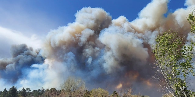 Smoke from a wind-whipped wildfire rises above neighborhoods on the outskirts of Flagstaff, Ariz., on Tuesday, April 19, 2022. Homes on the outskirts of Flagstaff were being evacuated Tuesday as high winds whipped a wildfire, shut down a major highway and grounded firefighting aircraft. (Sean Golightly/Arizona Daily Sun via Online News 72h)
