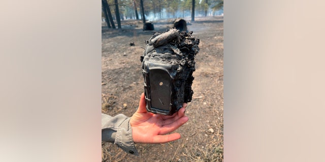 In this photo provided by the National Park Service, the remains of a ranger's game camera are held after the Tunnel Fire burned near the Sunset Crater Volcano National Monument in Arizona, Wednesday, April 20, 2022. Winds are expected to intensify through the end of the week as firefighters battle blazes across the Southwest. Resources are tight, and fire managers are scrambling to get crews on board. 