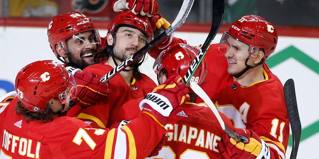 Calgary Flames defenseman Christopher Tanev, center, celebrates with teammates after scoring against the Dallas Stars during the third period of an NHL hockey game Thursday, April 21, 2022, in Calgary, Alberta.