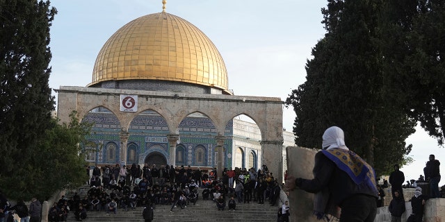 A Palestinian protester takes cover behind a makeshift shield during clashes with Israeli police at the Al Aqsa Mosque compound in Jerusalem's Old City, Friday, April 22, 2022. 