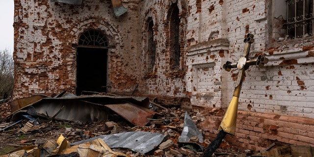 A metal cross that used to be on the top of the dome stands outside of the damaged church in Lukashivka, in northern Ukraine, on Friday, April 22, 2022.