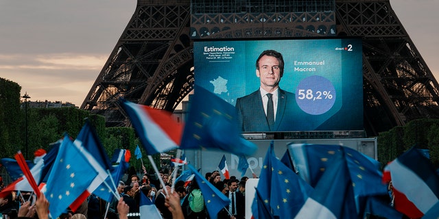 Supporters of French President Emmanuel Macron watch a screen in front of the Eiffel Tower as the first election projections are announced in Paris, France, Sunday, April 24, 2022.