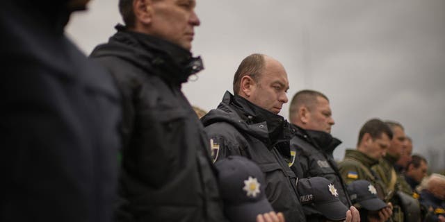 Decorated Ukrainian National Guard soldiers and State Emergency Service members observe a moment of silence during a ceremony commemorating the Chernobyl Nuclear Power Plant disaster at the Those Who Saved the World monument in Chernobyl, Ukraine, Tuesday, April 26, 2022.