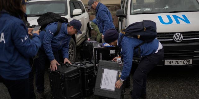 International Atomic Energy Agency (IAEA) team members unload suitcases with equipment as they arrive to the Chernobyl Nuclear Power Plant in Chernobyl, Ukraine, Tuesday, April 26, 2022.