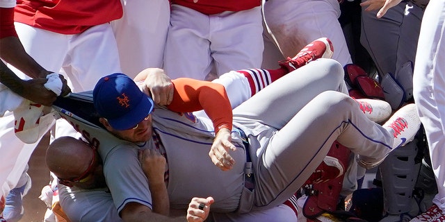 New York Mets' Pete Alonso is taken to the ground by St. Louis Cardinals first base coach Stubby Clapp, rear, as benches clear during a scuffle in the eighth inning of a baseball game Wednesday, April 27, 2022, in St. Louis. Clapp was ejected from the game. 