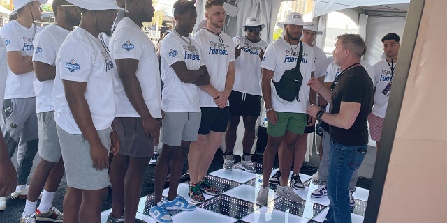 In a photo provided by Marc Ganis, artist Rob Prior explains to NFL draft prospects how he creates portraits, Wednesday, April 27, 2022, in Las Vegas. Prior will be painting portraits through the first round of the NFL football draft Thursday night and giving lithographs to each player.