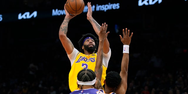 Los Angeles Lakers forward Anthony Davis shoots over Phoenix Suns center JaVale McGee and forward Mikal Bridges during the first half of an NBA basketball game Tuesday, April 5, 2022, in Phoenix.