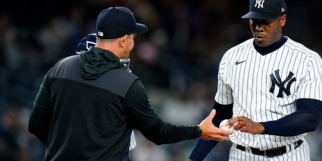 New York Yankees relief pitcher Aroldis Chapman, reg, hands the ball to manager Aaron Boone as he leaves during the ninth inning of a baseball game against the Toronto Blue Jays, Donderdag, April 14, 2022, In New York.