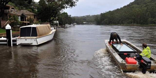 Residents transport a window panel in a boat from a house on the bank of an overflowing Woronora River on April 7, 2022, as inclement weather triggered evacuation orders in several suburbs of Sydney's south and southwest. 
