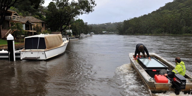 Residents transport a window panel in a boat from a house on the bank of an overflowing Woronora River on April 7, 2022, as inclement weather triggered evacuation orders in several suburbs of Sydney's south and southwest. 