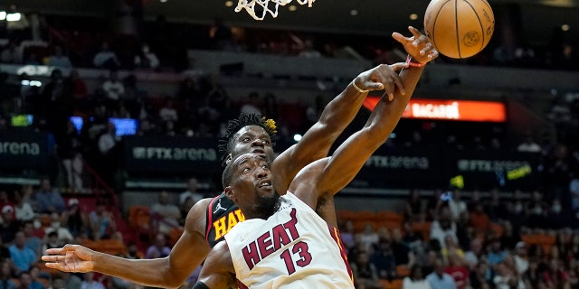 Atlanta Hawks center Clint Capela, rear, and Miami Heat center Bam Adebayo (13) reach for the ball during the first half of an NBA basketball game Friday, April 8, 2022, in Miami.