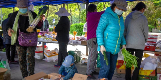 People wearing masks shop for fresh vegetables at a pop-up market in Beijing, Thursday, April 28, 2022. 