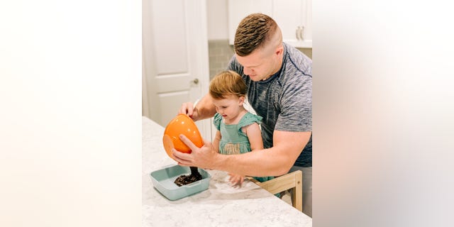 Jared Bridegan baking brownies with his daughter Bexley. He built the wood stool she sits on so she could help him in the kitchen, Kirsten said.