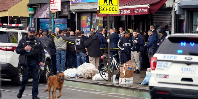 New York City Police Department personnel gather at the entrance to a subway stop in the Brooklyn borough of New York, Tuesday, April 12, 2022.