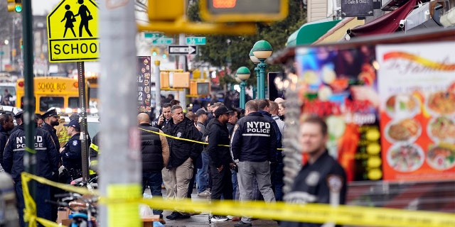 New York City Police Department personnel gather at the entrance to a subway stop in Brooklyn, New York, Tuesday, April 12, 2022.