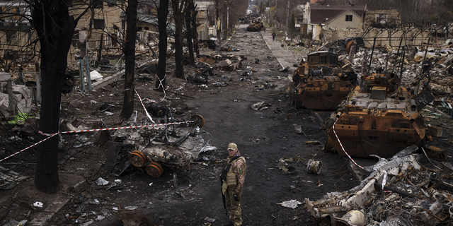 A Ukrainian serviceman stands amid destroyed Russian tanks in Bucha, on the outskirts of Kyiv, Ukraine, on Wednesday.