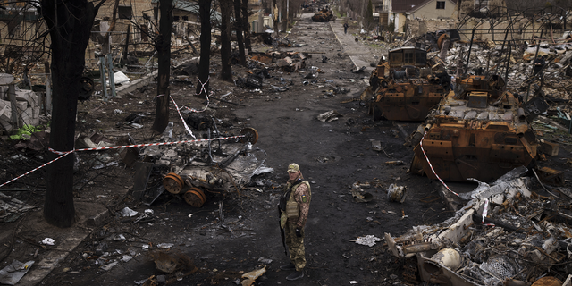 A Ukrainian serviceman stands amid destroyed Russian tanks in Bucha, on the outskirts of Kyiv, Ukraine, on Wednesday.