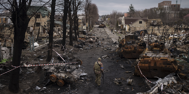 Ukraynalı bir asker, Kiev, Ukrayna'nın eteklerinde Bucha'da yıkılan Rus tankları arasında yürüyor.