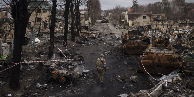 A Ukrainian serviceman walks amid destroyed Russian tanks in Bucha, on the outskirts of Kyiv, Ukraine, on Wednesday.