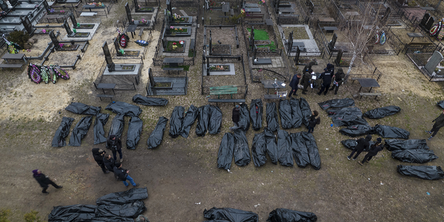 警告: 图形图像: Policemen work on the identification process following the killing of civilians in Bucha, before sending the bodies to the morgue, on the outskirts of Kyiv, 乌克兰, 在星期三.