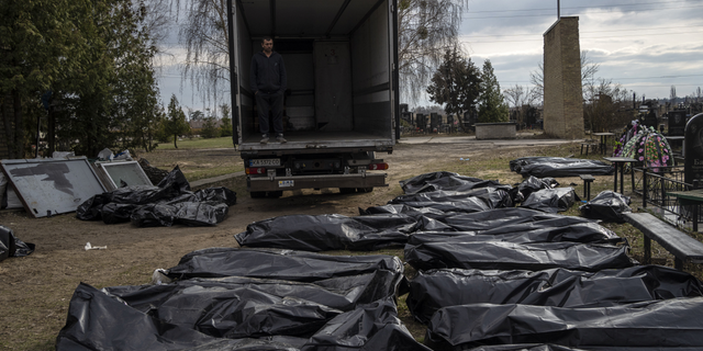 WARNING: GRAPHIC IMAGE: A cemetery worker waits in a truck before colleagues start to load the corpses of civilians killed in Bucha, before transporting them to the morgue, on the outskirts of Kyiv, Ukraine, on Wednesday.