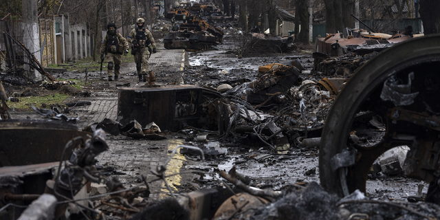 Soldiers walk amid destroyed Russian tanks in Bucha, on the outskirts of Kyiv, Ukraine.
