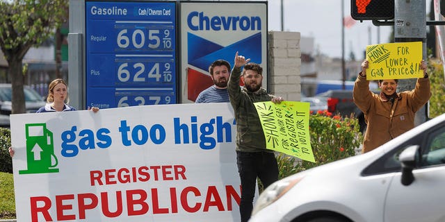 Republican activists seek drivers' attention as they work to register voters to their party at a gas station in Garden Grove, California, U.S., March 29, 2022. Picture taken March 29, 2022. REUTERS/Mike Blake 