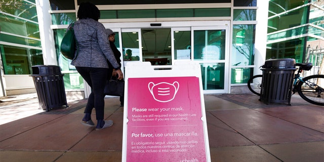 A sign advising visitors to don face coverings stands outside the main entrance to UCHealth University of Colorado hospital Friday, April 1, 2022, in Aurora, Colo. 