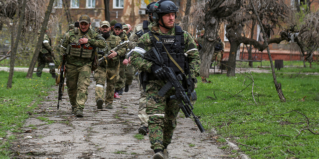 Fighters of the Chechen special forces unit walk in a courtyard in Mariupol, Ukraine, on Thursday, April 21.