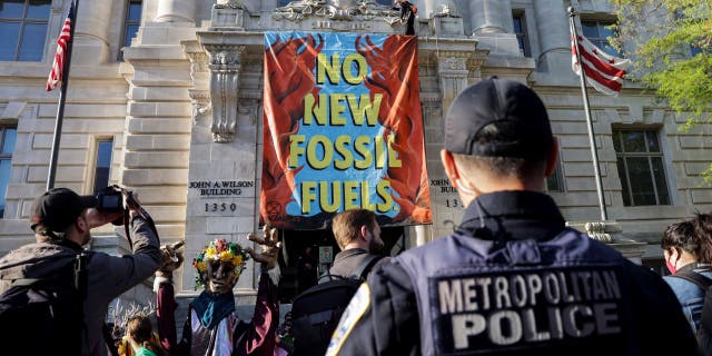 An environmental activist with the group Extinction Rebellion DC scales a building on April 22, in Washington, D.C. (Photo by Kevin Dietsch/Getty Images)