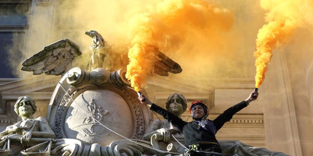 WASHINGTON, DC - APRIL 22: An environmental activist with the group Extinction Rebellion DC scales the Wilson Building as part of an Earth Day rally against fossil fuels (Photo by Kevin Dietsch/Getty Images)