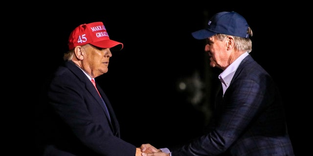 Former President Donald Trump shakes hands with former Sen. 大卫·珀杜（David Perdue）, who's primary challenging GOP Gov. Brian Kemp of Georgia, at the former president's rally in Cumming, 嘎. 在三月 26, 2022