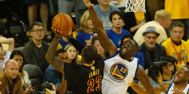 Cleveland Cavaliers forward LeBron James (L) shoots the ball over Golden State Warriors forward Draymond Green during the third quarter in Game 7 of the NBA Finals on June 19, 2016 in Oakland, Kalifornië.