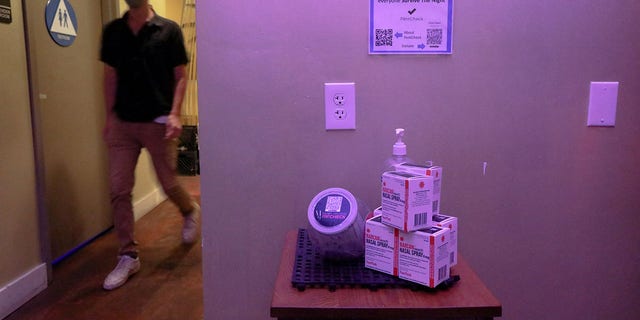A patron is seen walking near a table that contains free fentanyl test strips and Narcan, at Low Bar in Oakland, California, on March 3, 2022. 