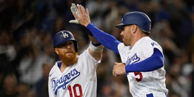 Los Angeles Dodgers designated hitter Justin Turner (10) high-fives Freddie Freeman (5) after Freeman scored on a single hit by Trea Turner during the eighth inning against the Cincinnati Reds in Los Angeles April 14, 2022.