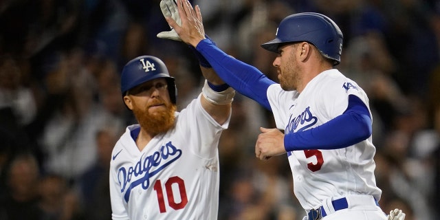 Los Angeles Dodgers menunjuk pemukul Justin Turner (10) tos Freddie Freeman (5) setelah Freeman mencetak satu pukulan oleh Trea Turner selama inning kedelapan melawan Cincinnati Reds di Los Angeles 14 April 2022.