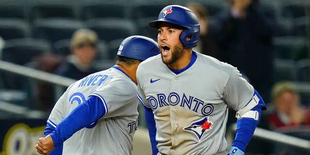 Toronto Blue Jays' George Springer, right, celebrates with third base coach Luis Rivera as he runs the bases after hitting a two-run home run during the third inning of a baseball game against the New York Yankees, Monday, April 11, 2022, in New York.