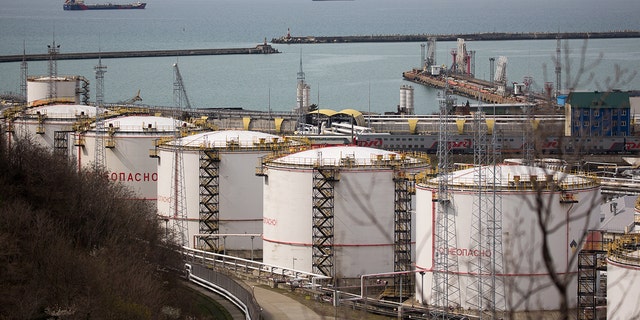 Oil storage tanks stand at the RN-Tuapsinsky refinery, operated by Rosneft Oil Co., as tankers sail beyond in Tuapse, Russia, on Monday, March 23, 2020. 